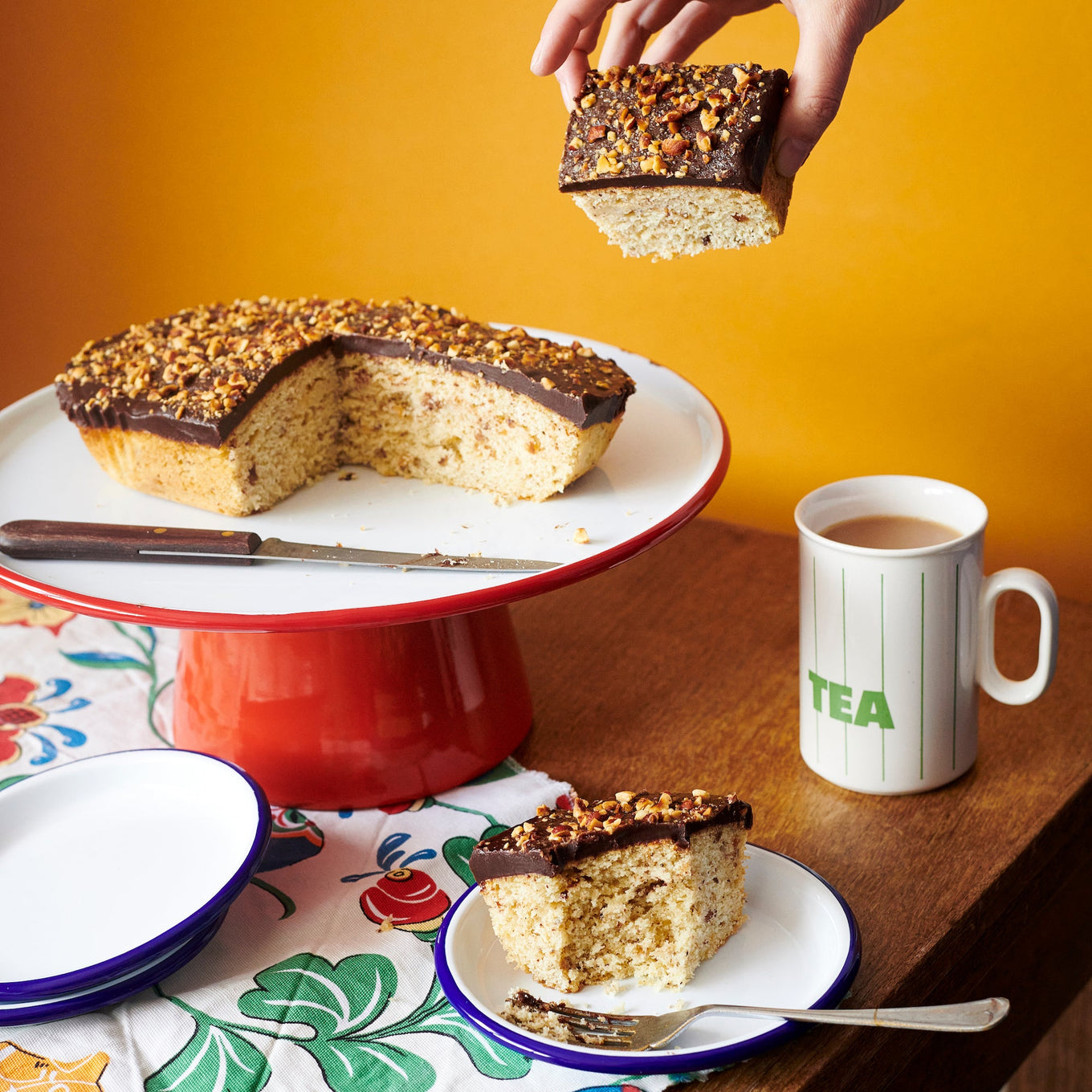 Exploding Bakery Ambassador's Cake on a Falcon Enamel Cake Stand portioned up with a cup of tea