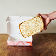 Hummingbird cake with pecans on top held above its box on a wooden table