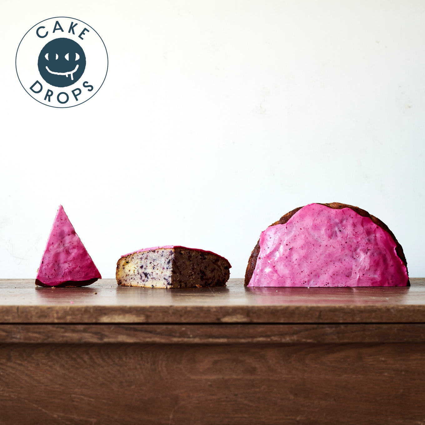 Three slices of Blueberry Cake photographed from the side on a Woden table