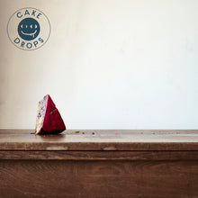 A slice of Blueberry Cake photographed from the side on a Woden table