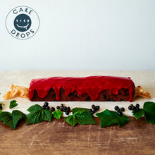 Blackcurrant Friand Loaf displayed with the leaves and berries from a blackcurrant bush.