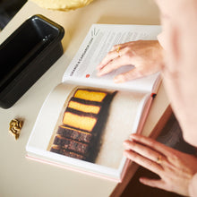 A person reading an Exploding Bakery cook book.