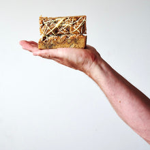 Two slices of Miso Blondie with white chocolate drizzle in the palm of a hand.