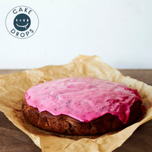 A whole Blueberry Cake photographed from the side on a Woden table