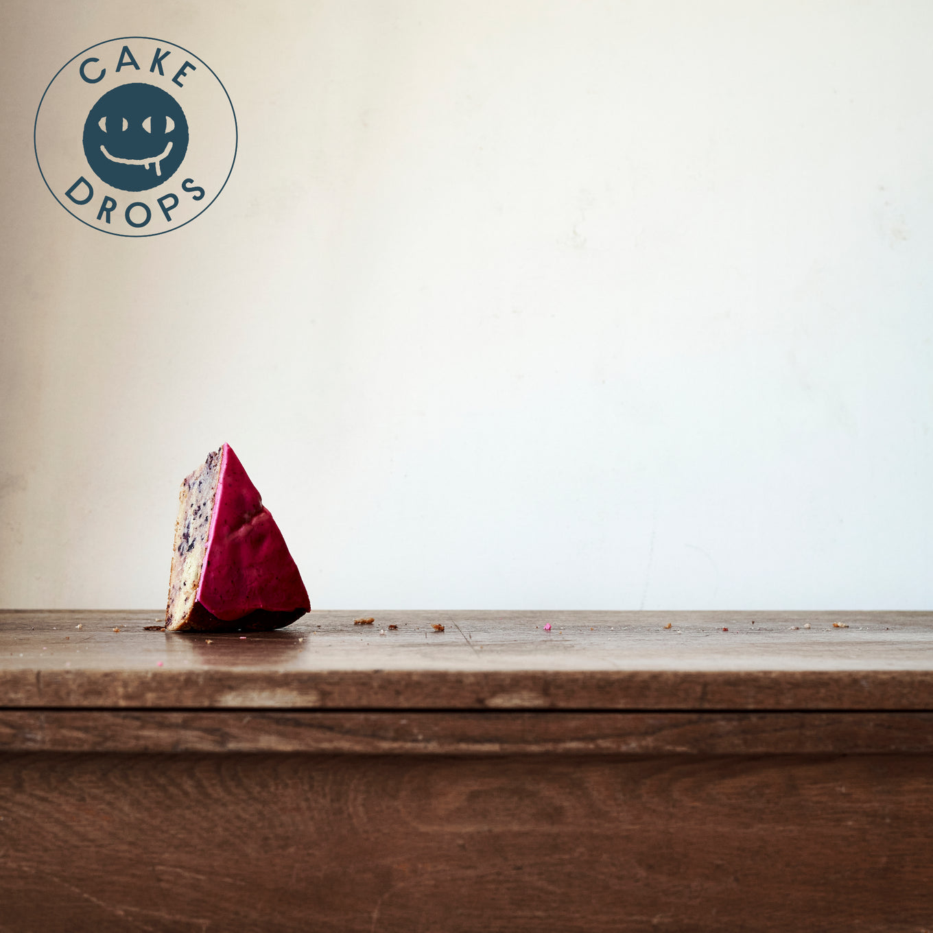 A slice of Blueberry Cake photographed from the side on a Woden table