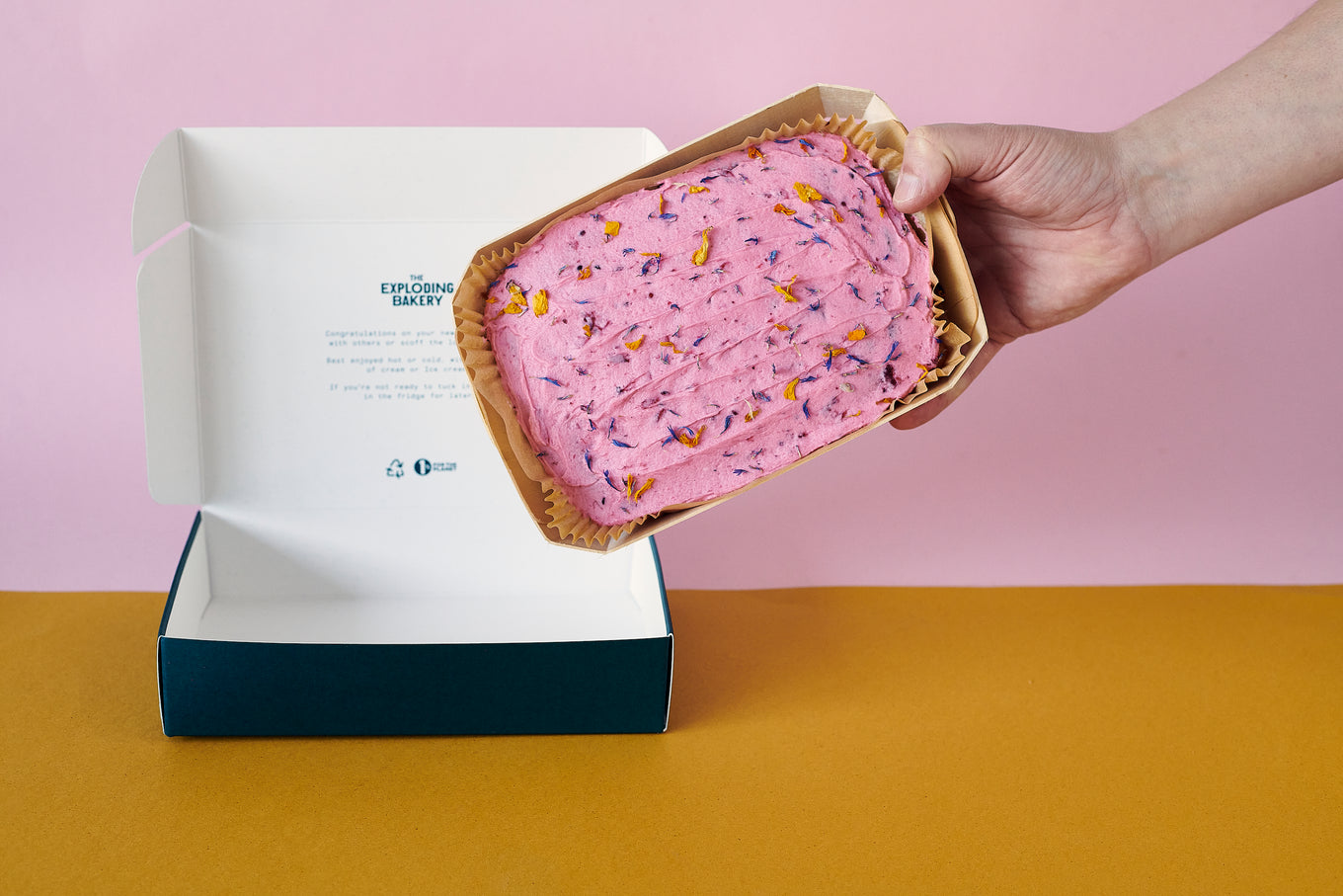 Someone Holding The Berry Citrus Cake Next To Exploding Bakery Deli Box