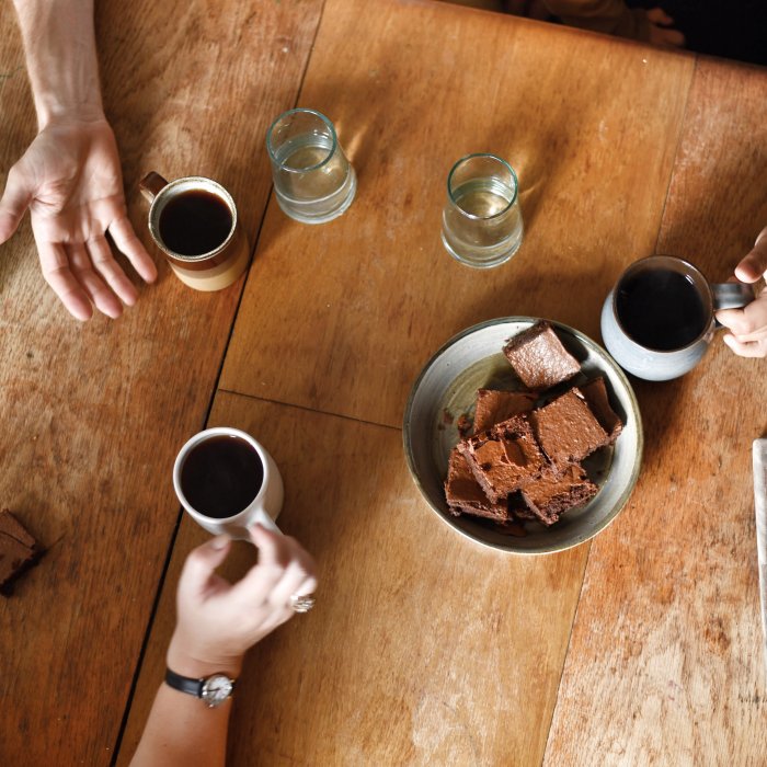 People enjoying a cup of coffee with Exploding Bakery brownie.