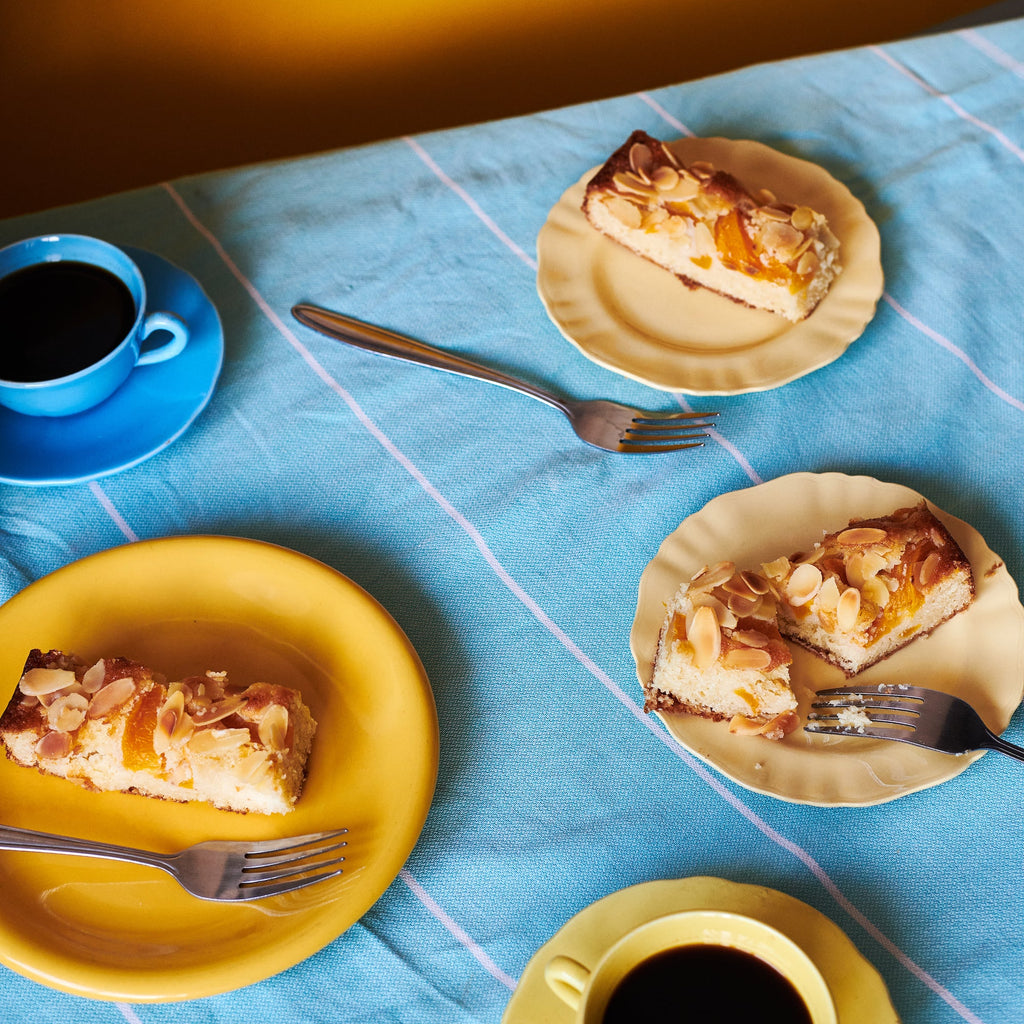 3 slices of Peach, Ricotta & Almond Cake plated u on a table wit coffee.