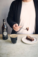 A slice of Black Velvet Cake with a bottle of Mena Dhu next to it