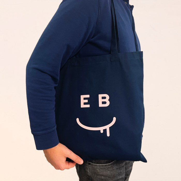 Canvas bag on the shoulder showing  EB logo 'drool face'