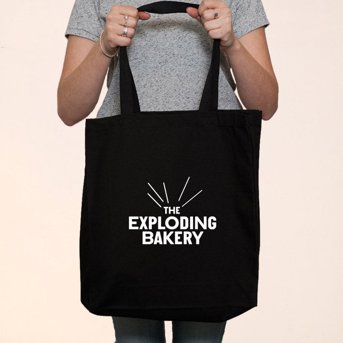 Someone holding an Exploding Bakery Tote Bag. 